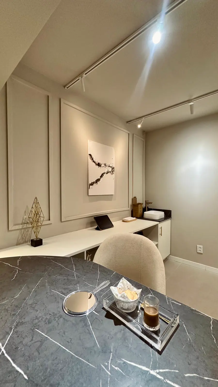 Sala Refúgio: bancada clara, mesa de mármore e trilho de luz
