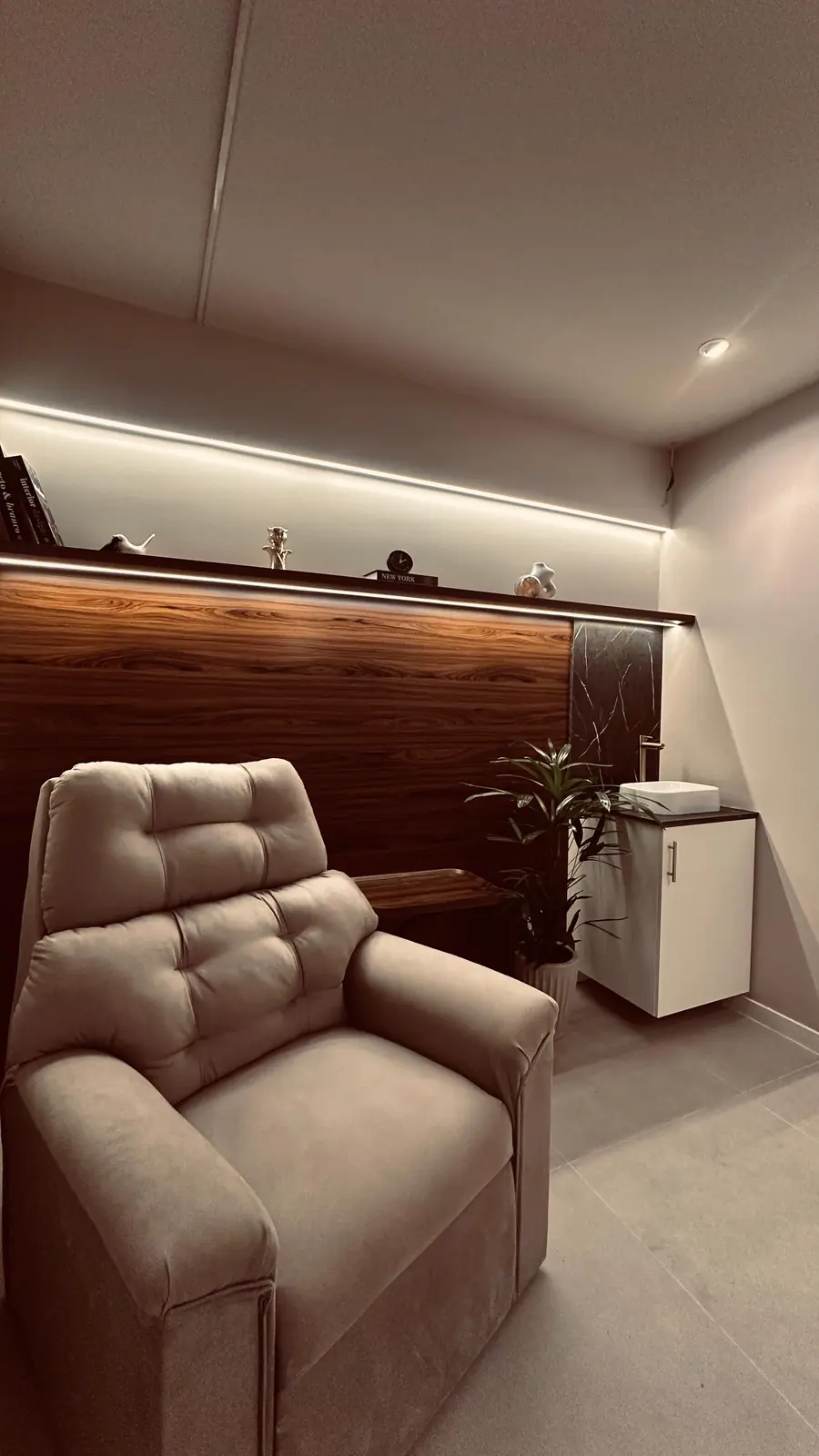 Sala Serenar: poltrona reclinável diante de painel de madeira iluminado